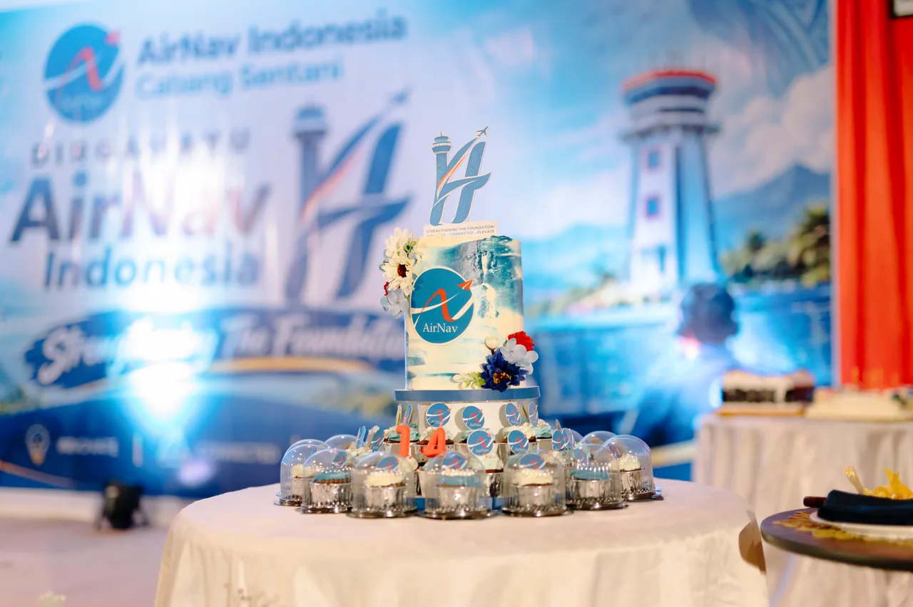 Kue peringatan HUT ke-14 AirNav Indonesia Cabang Sentani di depan backdrop acara